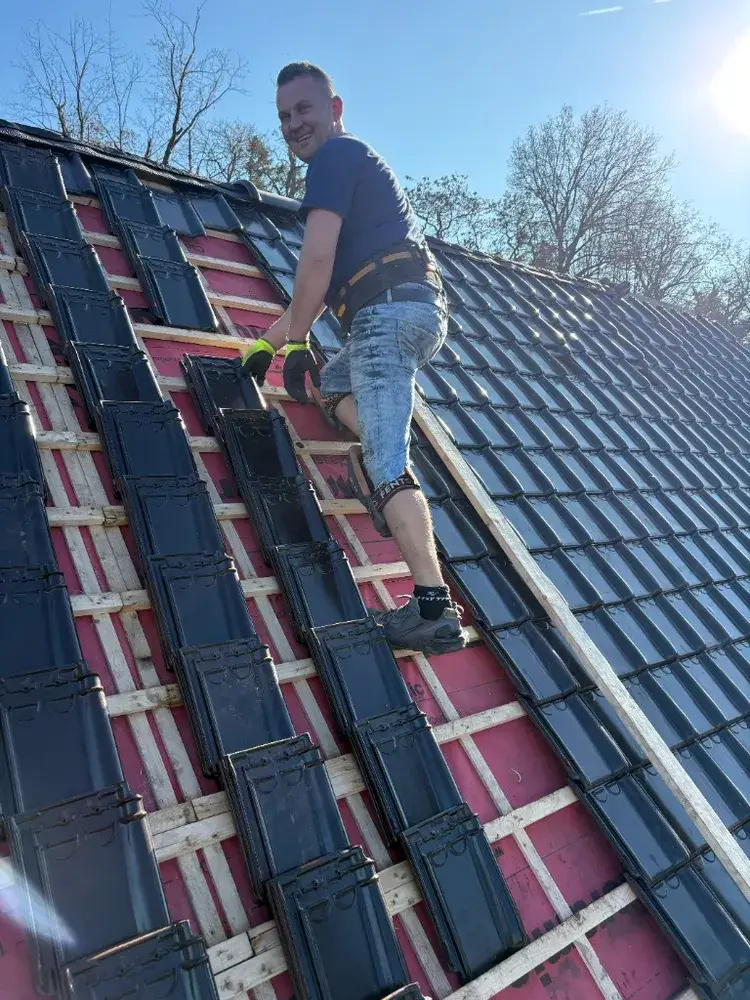 Dakdekker legt zwarte dakpannen op een schuin dak